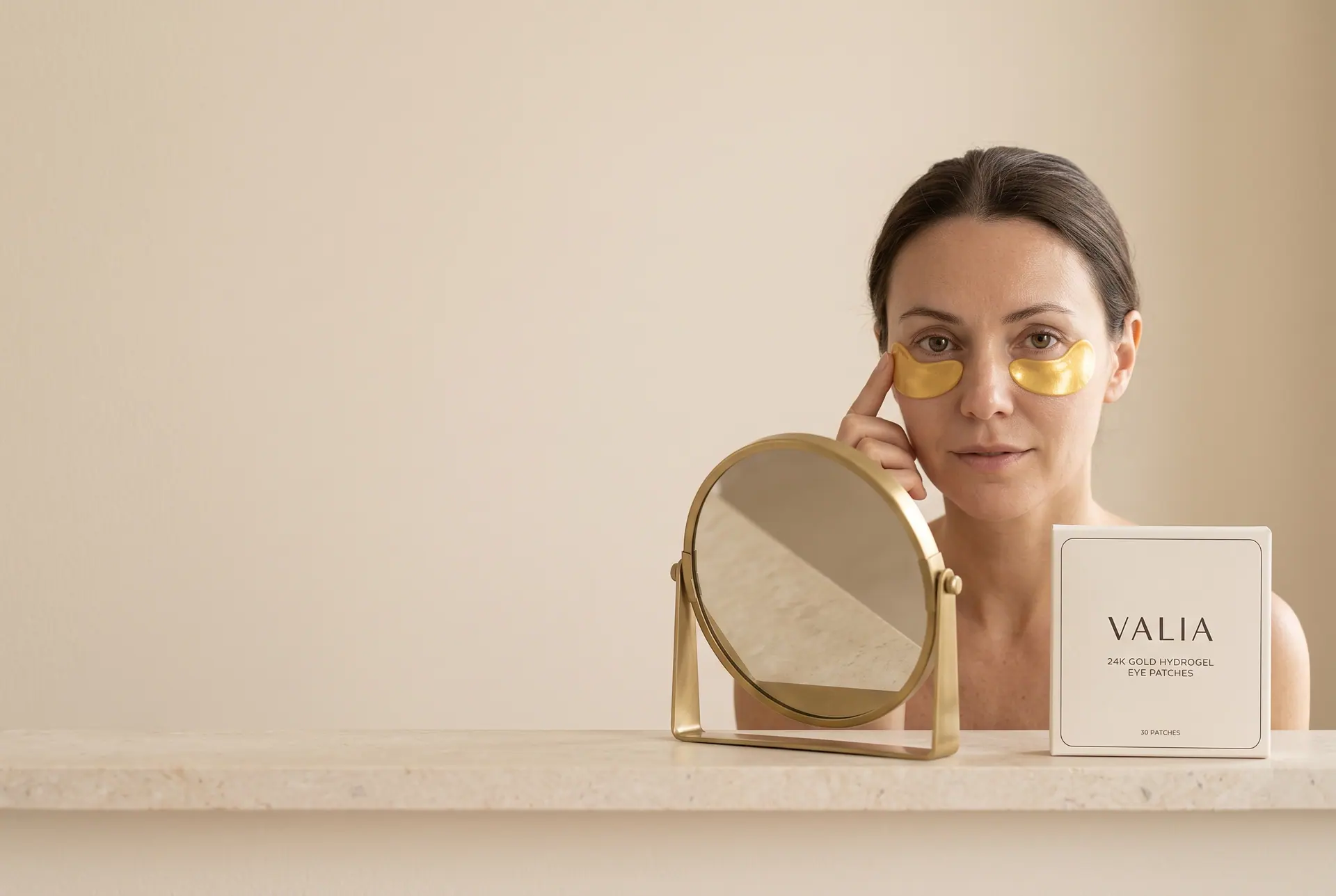 A fingertip smoothing a gold crescent under one eye at a small mirror, morning light.