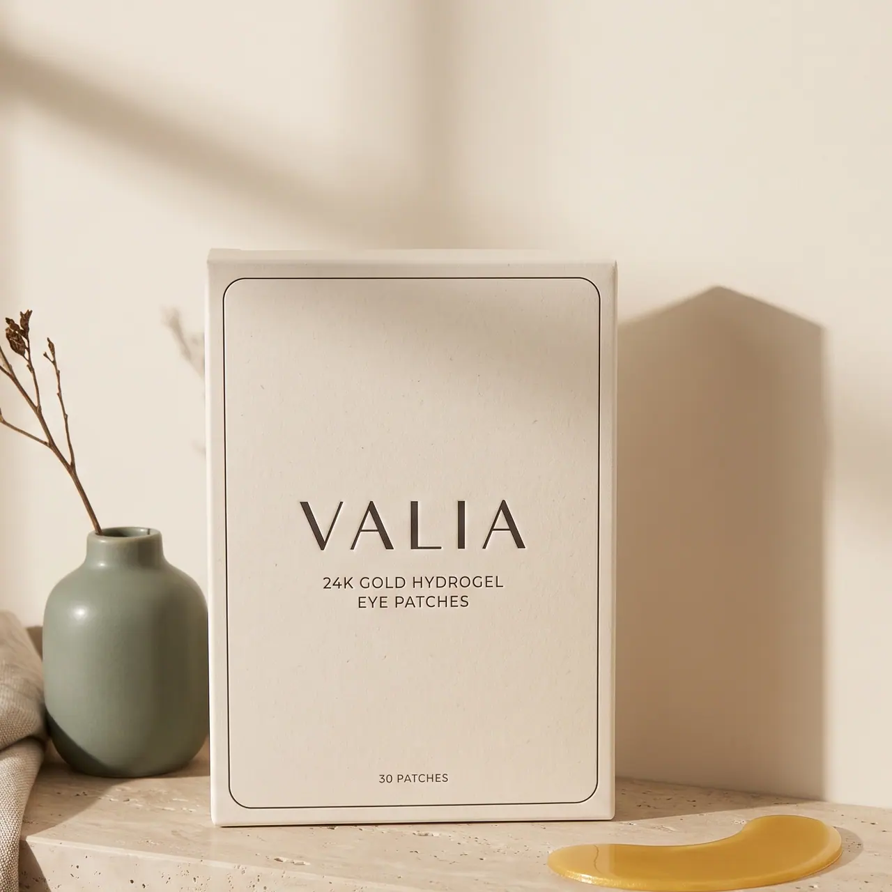 The VALIA box standing on a travertine ledge beside a sage vase and a folded linen towel.
